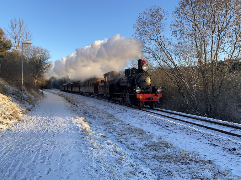 Lennakattens ånglok med tåg i vinterlandskap.